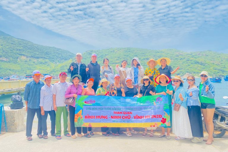 Đoàn khách tham gia tour đoàn Ninh Chữ Vĩnh Hy check-in kỷ niệm bên bờ biển xanh ngắt.